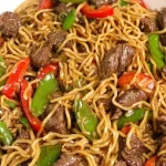 Spetterende knoflook-sojabeef geserveerd met noedels en krokante groenten