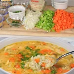 Een kom Oma's Kippensoep, rijk aan verse ingrediënten en kruiden.