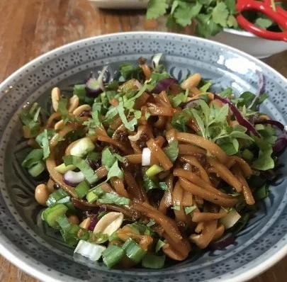 Pittige rijstnoedelsalade met kleurrijke groenten en kruiden.