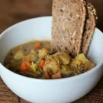 Vegan linzen soep geserveerd met soja yoghurt en verse kruiden