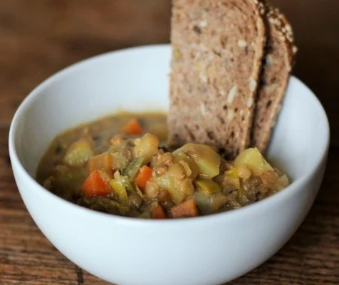 Vegan linzen soep geserveerd met soja yoghurt en verse kruiden